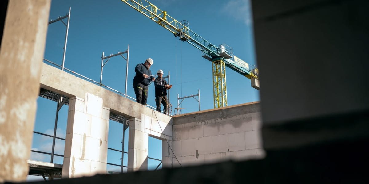 Deux artisans sur un chantier, plans à la main